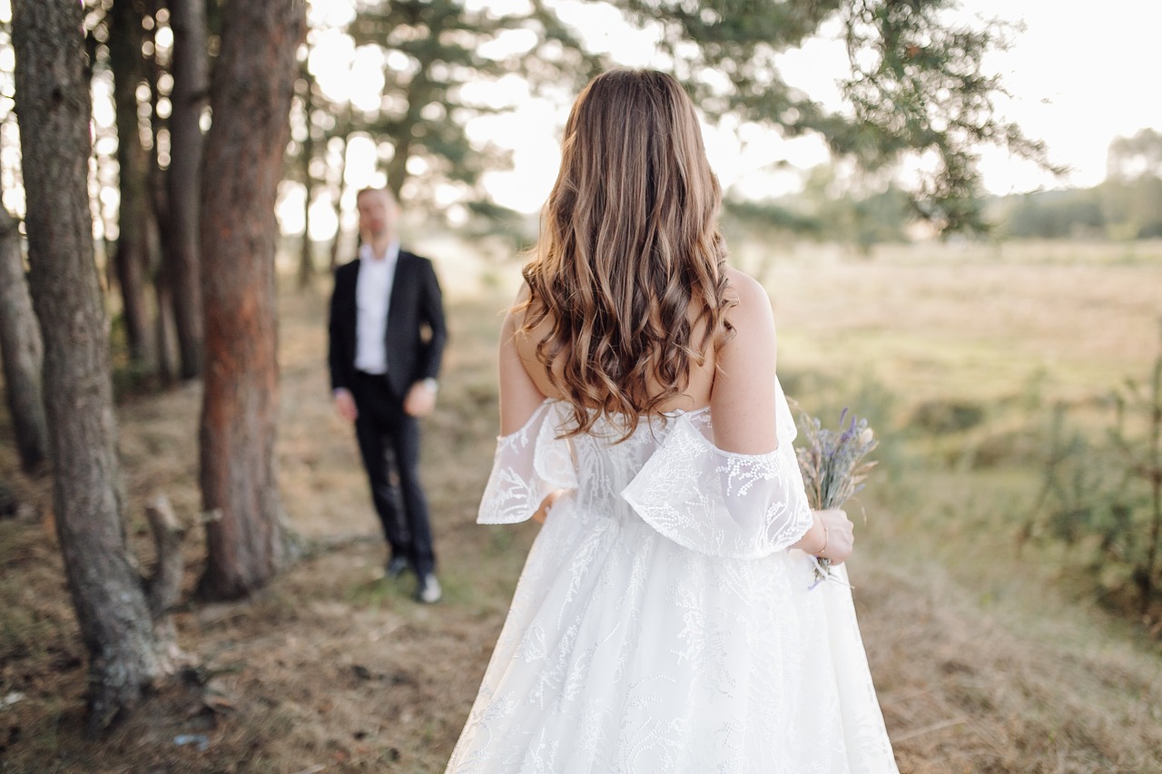 A bride in a beautiful gown walking towards the groom at a wedding venue, capturing a romantic and intimate moment.