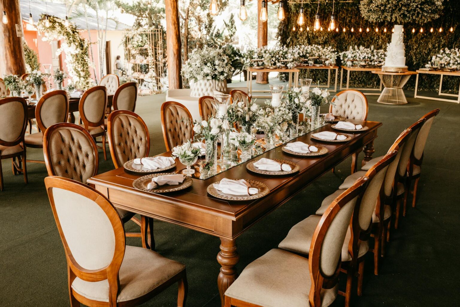 Intimate wedding reception with rustic-themed table seating and white rose flower arrangements in the table setting.