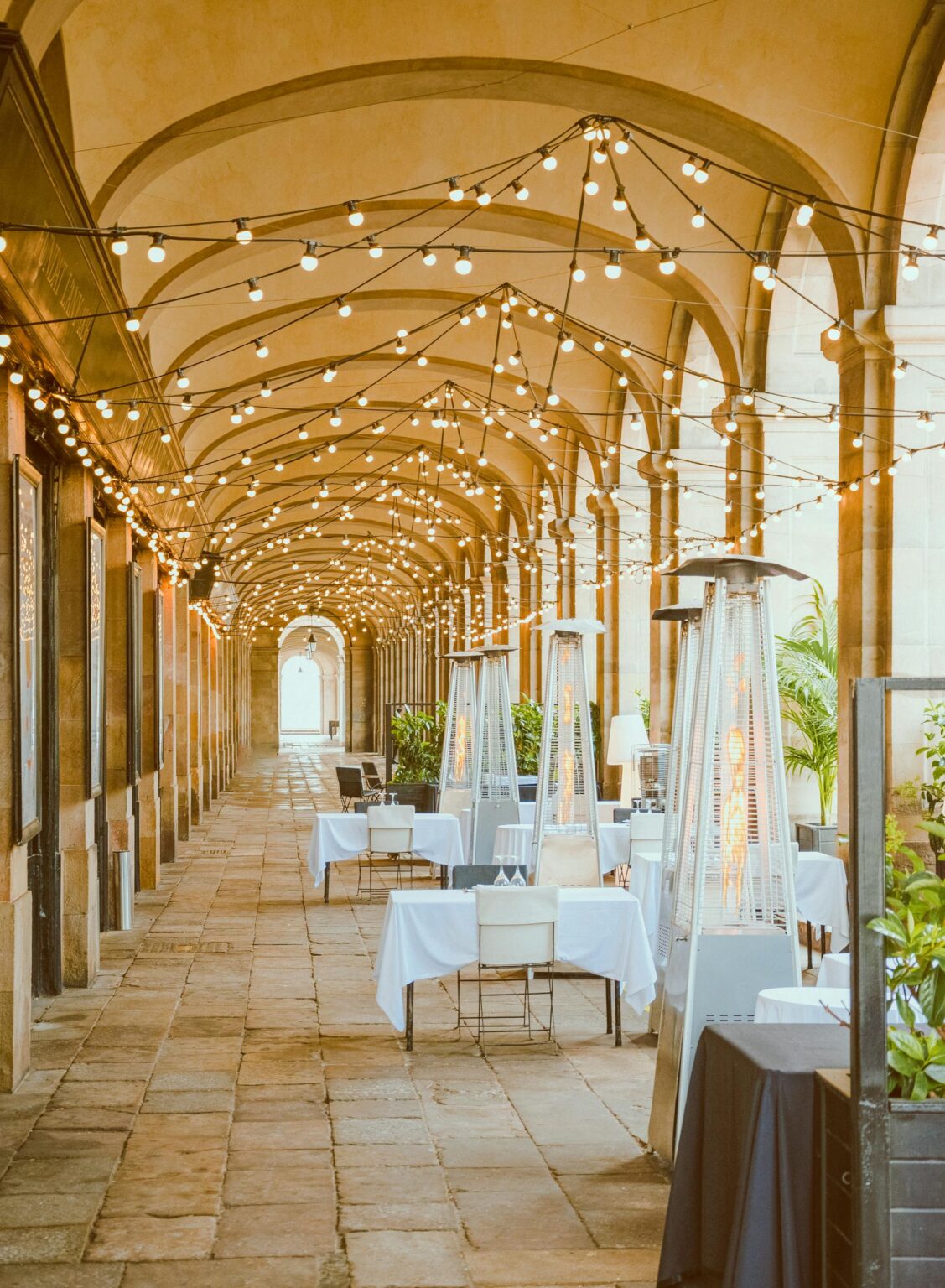 A beautifully designed hallway with architectural pillars, set up for a wedding reception, offering a unique and almost outdoor atmosphere.